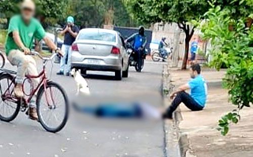 divulgação - Vigilante ficou sentado ao lado da vítima esfaqueada, caída no asfalto: ele fugiu na sequência após ser ameaçado por moradores